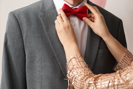 Young woman fixing her prom date's bow, closeupの写真素材