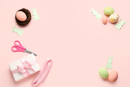 Frame made of Easter eggs, gift and paper rabbits on pink backgroundの写真素材