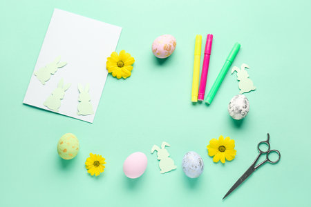 Frame made of blank paper sheet, rabbits, Easter eggs, felt-tip pens and flowers on green backgroundの写真素材