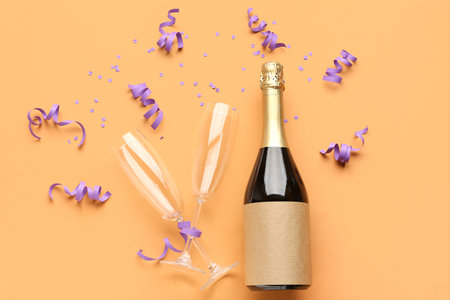 Bottle of champagne, glasses, serpentine and sequins on orange backgroundの写真素材