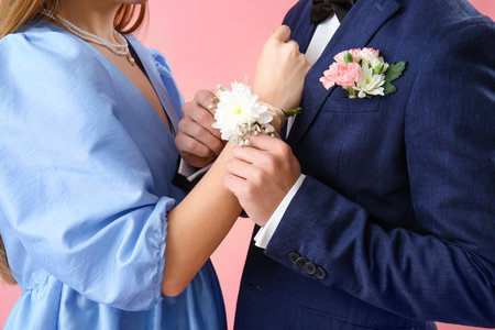 Young boy putting corsage on his prom date wrist against pink background, closeupの写真素材