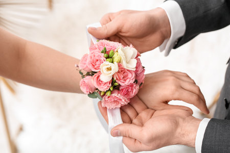 Young man tying corsage around his prom date's wrist, closeupの写真素材