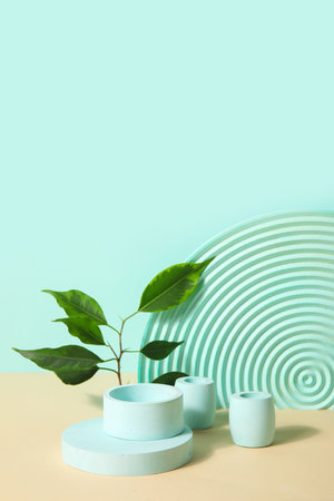 Plaster podiums and ficus branches on beige table against turquoise backgroundの写真素材