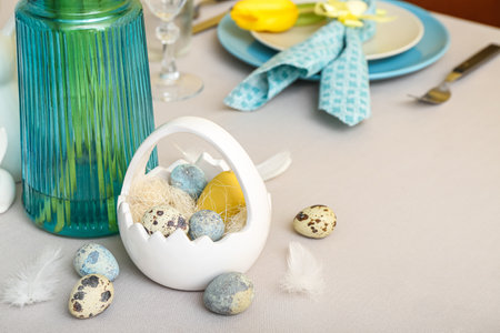 Basket with different eggs and feathers on table served for Easter celebration, closeup