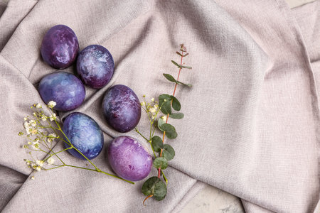 Painted Easter eggs, eucalyptus branch and gypsophila flowers on gray tableclothの写真素材