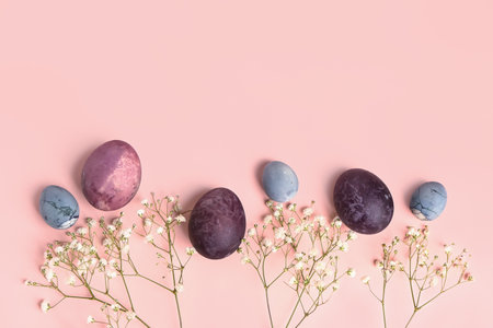 Composition with painted Easter eggs and gypsophila flowers on pink background