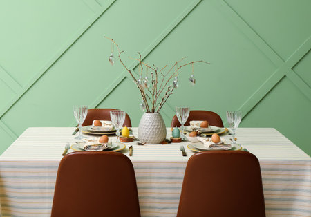 Festive dining table with eggs and pussy willow branches served for Easter celebration near green...