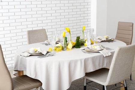 Festive dining table served for Easter celebration near white brick wallの写真素材