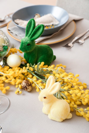 Bunnies, eggs and mimosa flowers on table served for Easter celebration
