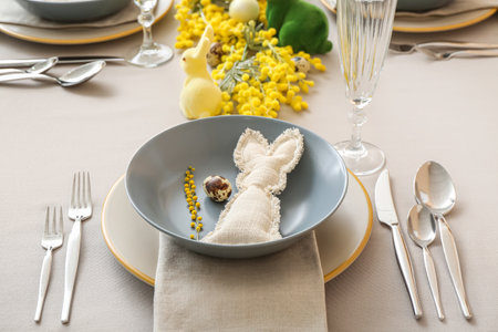 Festive table setting with eggs, bunnies and mimosa flowers served for Easter celebration