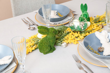 Bunnies, eggs and mimosa flowers on table served for Easter celebration