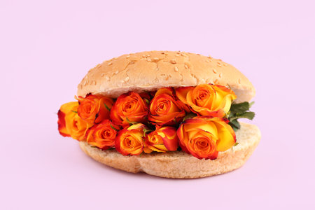 Burger bun with beautiful rose flowers on pink backgroundの写真素材