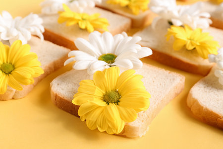 Composition with slices of bread and beautiful chrysanthemum flowers on yellow background, closeupの写真素材