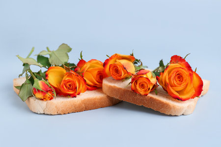 Slices of bread with beautiful rose flowers on light background