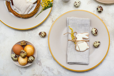 Table setting with Easter eggs and mimosa flowers on white grunge background