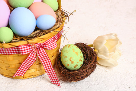Wicker basket with painted Easter eggs and tulip flowers on white background