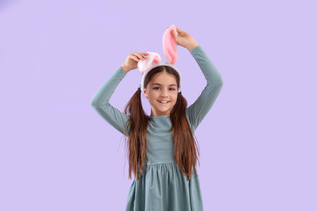 Little girl in bunny ears on lilac backgroundの写真素材