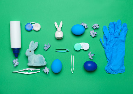 Ophthalmologist's tools with Easter eggs, rabbits and flowers on green background