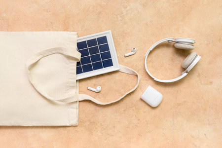 Composition with portable solar panel and wireless earphones on beige grunge backgroundの写真素材