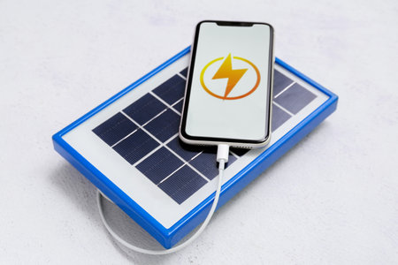 Portable solar panel charging mobile phone on white grunge backgroundの写真素材