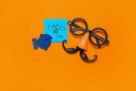 Sticky note with text FOOL'S DAY and party decor on color backgroundの写真素材