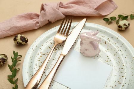 Stylish table setting with blank card and ceramic bunny on color background, closeup