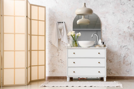 Interior of light bathroom with sink, drawers and folding screen