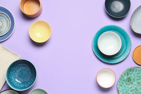 Composition with clean ceramic plates and bowls on lilac background