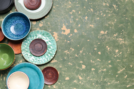 Composition with clean ceramic plates and bowls on green grunge backgroundの写真素材
