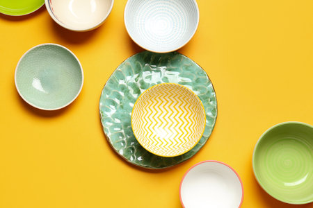 Composition with clean ceramic plates and bowls on orange backgroundの写真素材