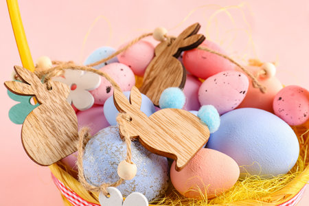 Basket with painted Easter eggs and garland on color background, closeup