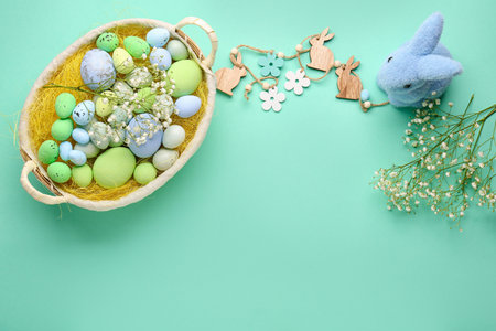 Composition with basket of painted Easter eggs, gypsophila flowers and decor on color backgroundの写真素材
