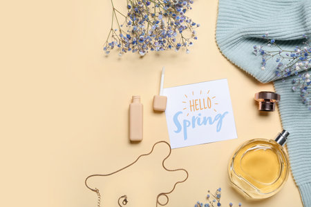 Card with text HELLO SPRING, cosmetics, gypsophila flowers and clothes on color backgroundの写真素材