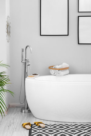Interior of light bathroom with bathtub and blank framesの写真素材