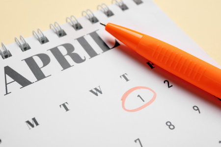 Calendar with marked date of April Fools' Day and pen on beige background, closeupの写真素材