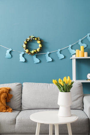 Interior of living room with Easter wreath, paper rabbits and sofa