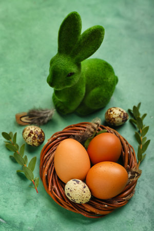 Nest with Easter eggs, eucalyptus branches and bunny on green grunge backgroundの写真素材