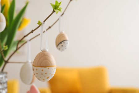 Tree branches with wooden Easter eggs in living room, closeupの写真素材