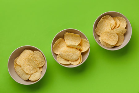 Bowls with delicious potato chips on green backgroundの写真素材