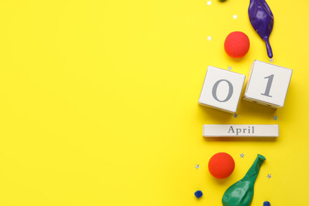 Composition with date 1 APRIL and party decor on yellow background. April Fool's Day celebrationの写真素材