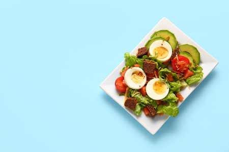 Plate of delicious salad with boiled eggs and salmon on blue backgroundの写真素材