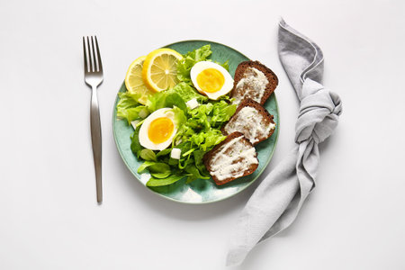 Plate of delicious salad with boiled eggs and cream cheese sandwiches on gray backgroundの写真素材