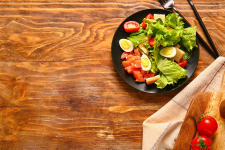 Plate of delicious salad with boiled eggs and salmon on brown wooden backgroundの写真素材