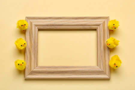 Composition with empty picture frame and toy chicks on color background
