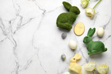 Easter bunnies, tulip flowers, cookies and painted eggs on white marble backgroundの写真素材