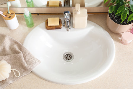 White sink and cosmetic products on table in roomの写真素材
