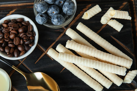 Delicious wafer rolls, blueberries and coffee beans on black board