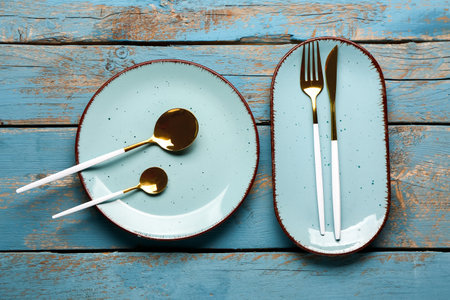 Plates with set of cutlery on blue wooden backgroundの写真素材