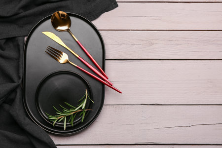 Tray with set of cutlery, plate and rosemary on white wooden background