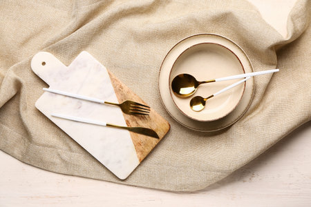 Board and bowl with set of cutlery on gray tableclothの写真素材